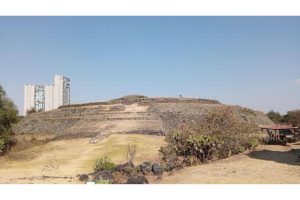 La pirámide de Cuicuilco, vista oeste desde el camino de acceso actual. Foto: Clément Girerd.En primer plano, el suelo es la superficie de lava del siglo III/IV. Detrás, la base de la pirámide sigue parcialmente atrapada en el flujo que la rodeaba por completo, pero que no pudo cubrirla..
